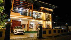 A two-story house with a car parked in the driveway.