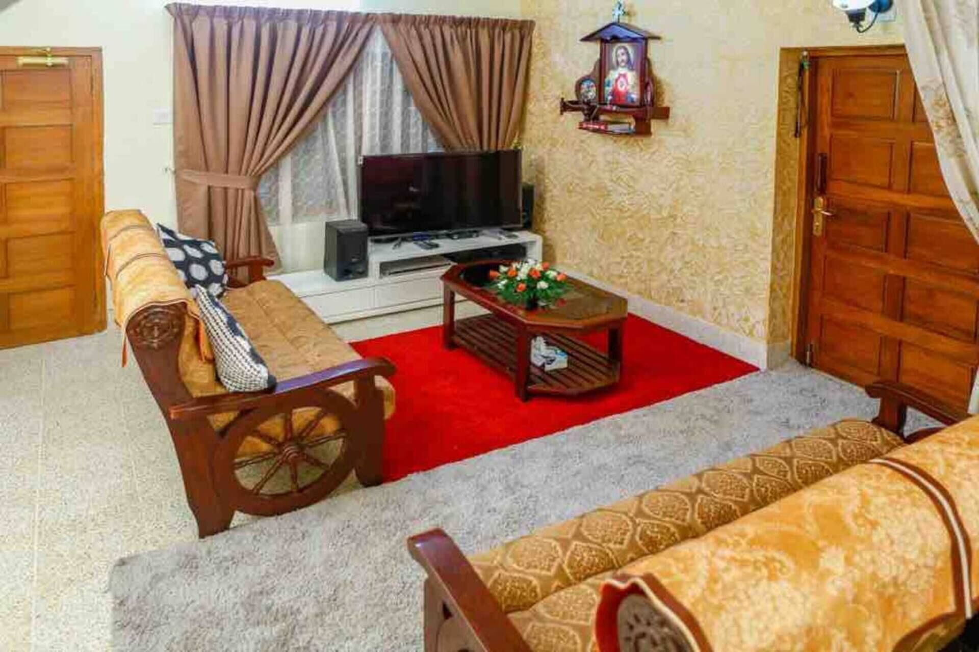 A living room with a sofa, a coffee table with flowers, a television, and a wall clock.