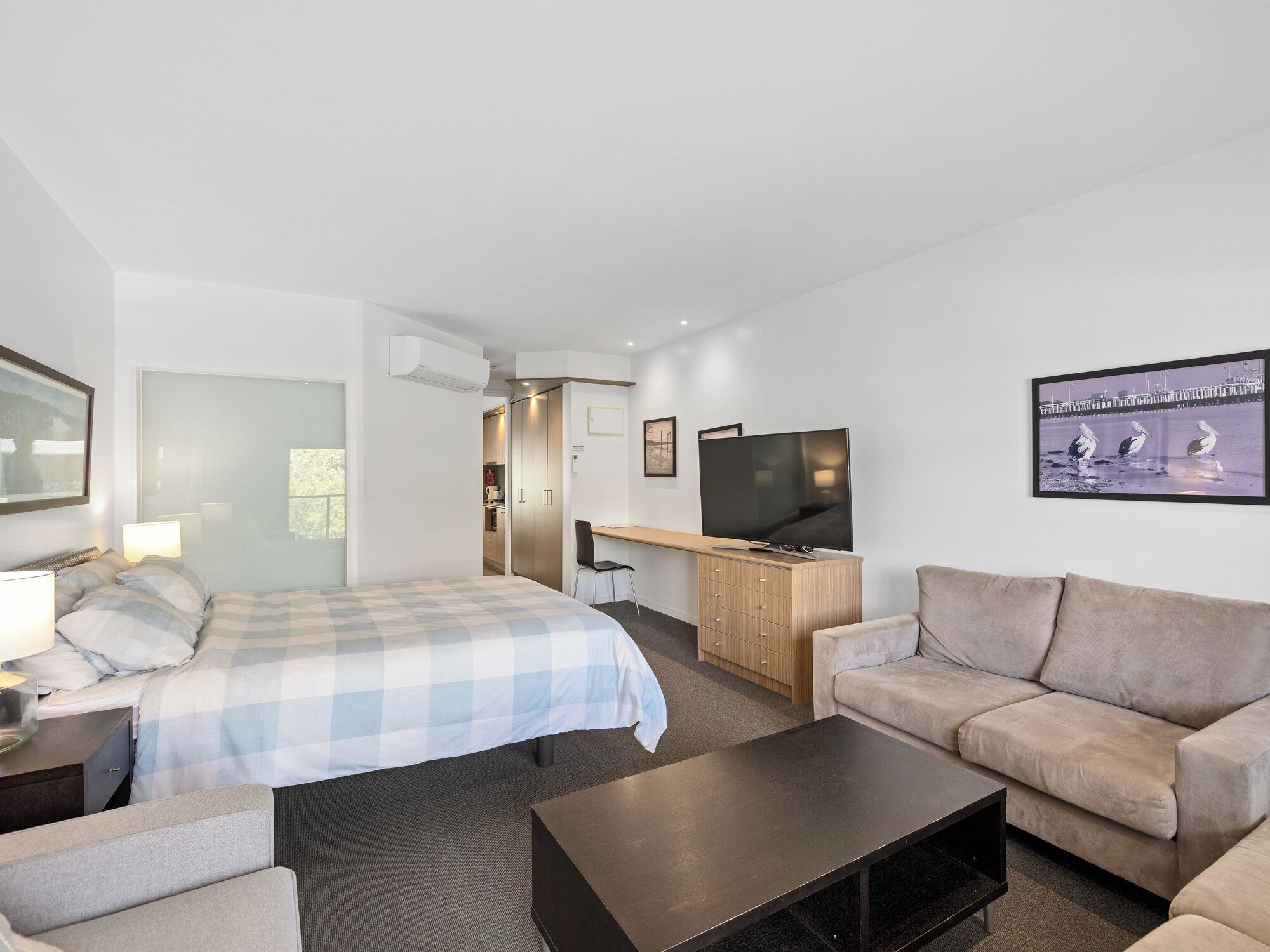 Une chambre d’hôtel moderne équipée d’un lit, d’un canapé, d’une télévision et d’un bureau.