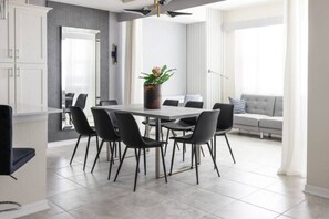 A modern dining area with a rectangular table surrounded by six chairs, a potted plant, and a large mirror on the wall.