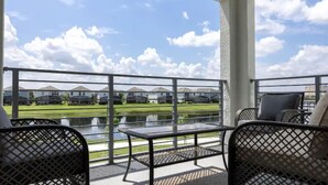 Un balcon donnant sur un lac, avec des maisons en arrière-plan.