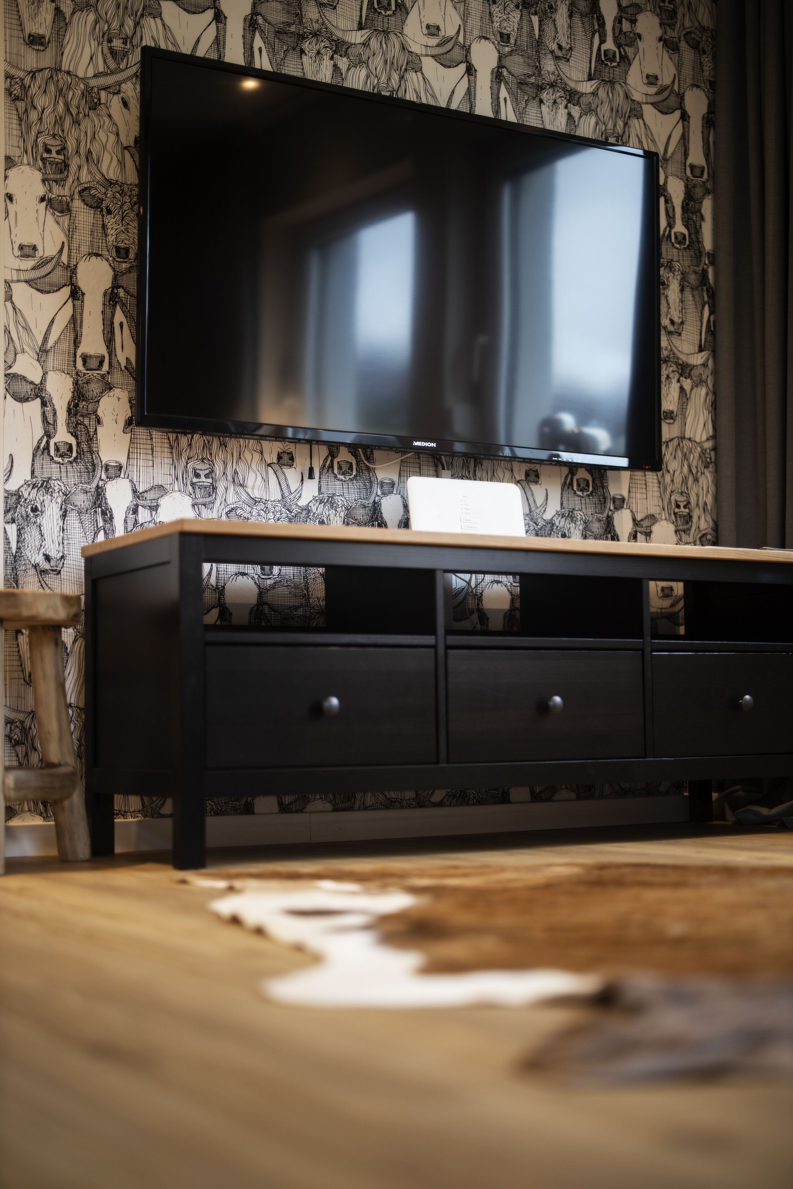 A modern living room with a flat-screen TV mounted on a wall with a detailed animal print wallpaper.