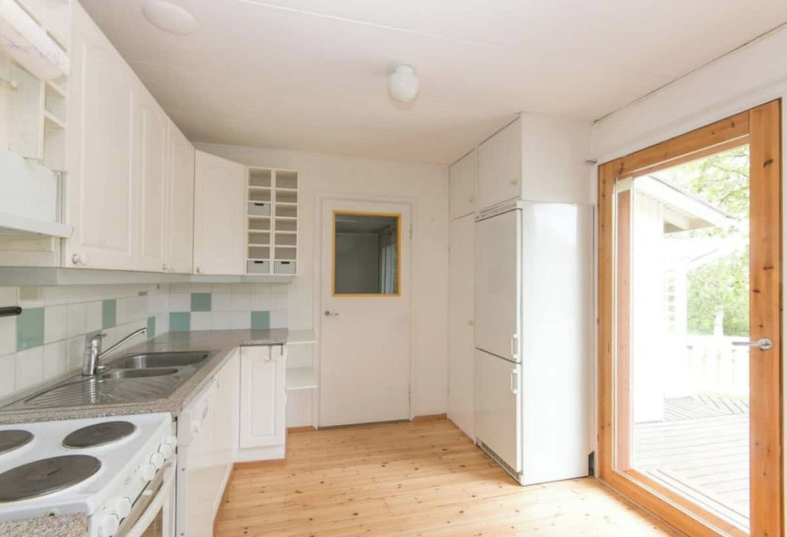 A compact kitchen with white cabinets, a stainless steel sink, a stove, and a refrigerator.