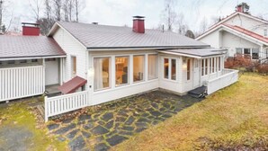 Ein zweistöckiges Haus mit einer Veranda und einer Steinterrasse.