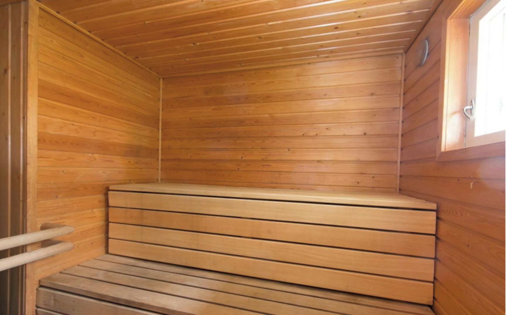A wooden sauna with a bench and a door.