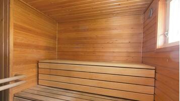 A wooden sauna with a bench and a door.