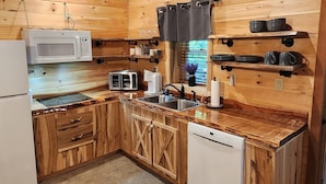 A wooden cabin-style kitchen with a built-in microwave, toaster, sink, and dishwasher. - Hocking Hills (Buck Crossing Retreat)  (Rockbridge)