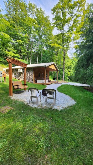 A rustic cabin with a porch, outdoor seating, and a gravel path leading to it. - Hocking Hills (Buck Crossing Retreat) (Rockbridge)