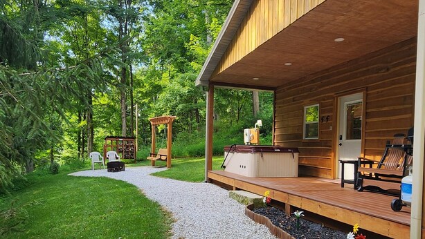 A wooden cabin with a covered porch, a hot tub, and a seating area. - Hocking Hills (Buck Crossing Retreat)  (Rockbridge)