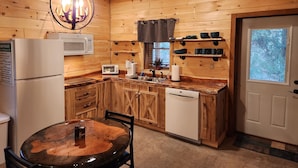 A wooden cabin interior with a kitchen featuring a microwave, toaster, coffee maker, and a dishwasher. - Hocking Hills (Buck Crossing Retreat)  (Rockbridge)