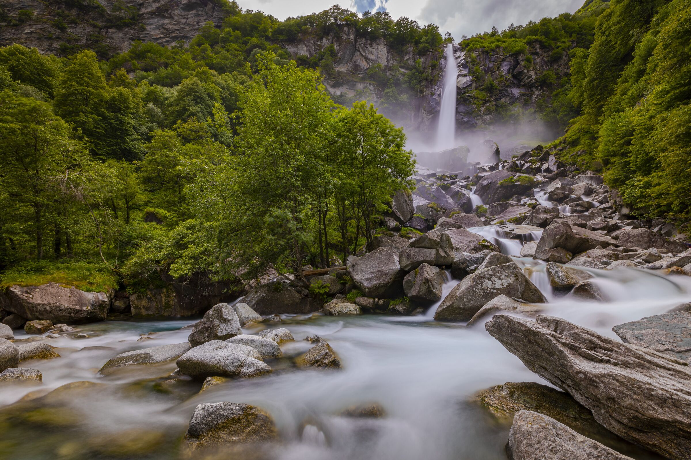 A natural landscape with a waterfall, rocks, and lush greenery.