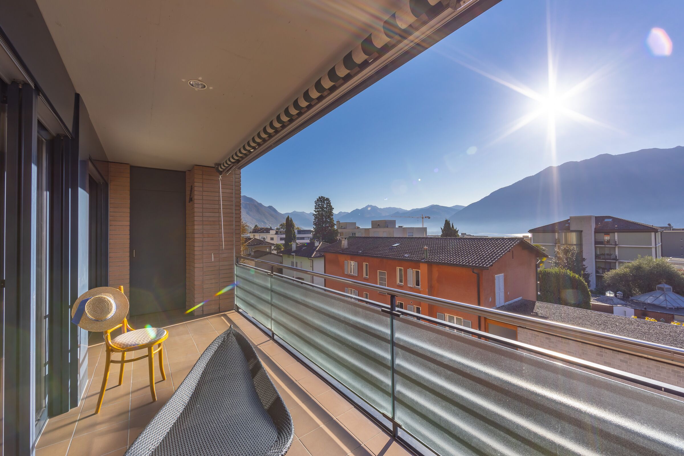 Un balcon avec une chaise et une petite table, d’où l’on peut admirer une montagne et une étendue d’eau.