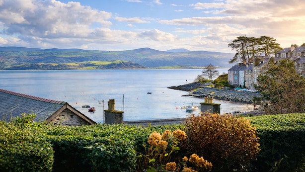 A coastal town with a view of the sea, a stone bridge, and buildings with a traditional architectural style.