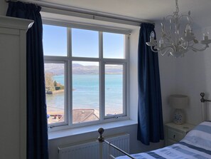 A bedroom with a large window offering a view of a lake and mountains. - 5 Star Cottage, Sleeps 8, Amazing Sea & Mountain Views, Borth y Gest, Wales (Borth-y-Gest)