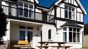 A two-story building with a balcony, a wooden bench, and a picnic table.