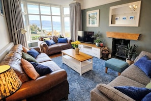A living room with a sofa set, a coffee table, a television, and a fireplace.