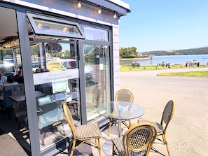 A glass-fronted cafe with wicker furniture and a view of a lake.