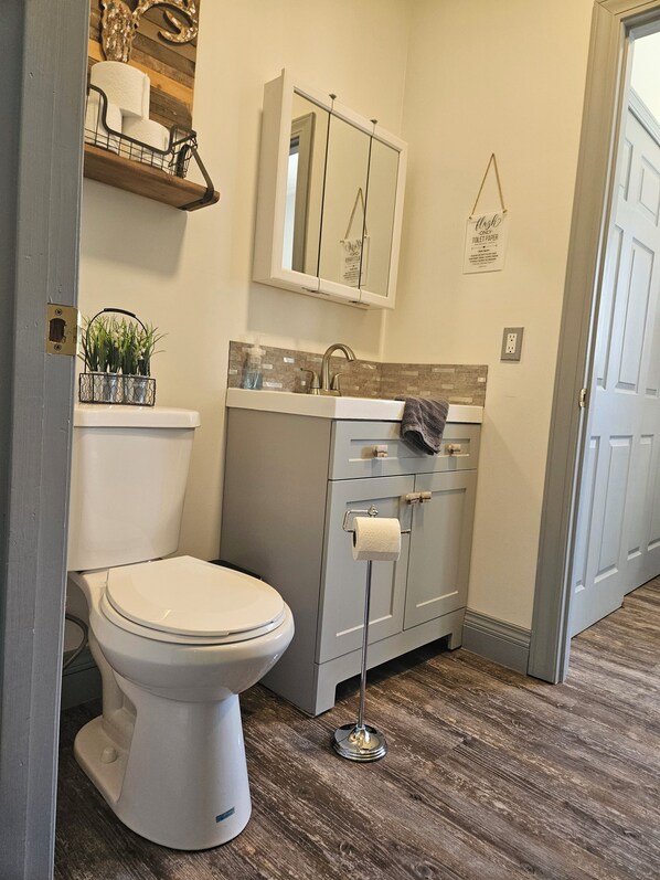 A bathroom with a toilet, a sink, a mirror, and a towel rack.