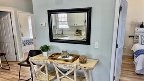 A dining area with a wooden table, two chairs, a mirror, and a small plant. - Ocean Lakes site 6013 beautiful 3 bedroom quiet street 2 carts available (Myrtle Beach)