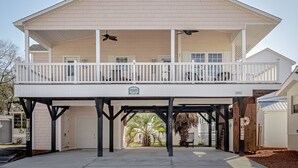 A two-story house with a balcony, a garage, and a covered patio area. - Ocean Lakes site 6013 beautiful 3 bedroom quiet street 2 carts available (Myrtle Beach)