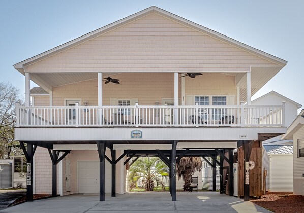 A two-story house with a balcony, a garage, and a covered patio area. - Ocean Lakes site 6013 beautiful 3 bedroom quiet street 2 carts available (Myrtle Beach)
