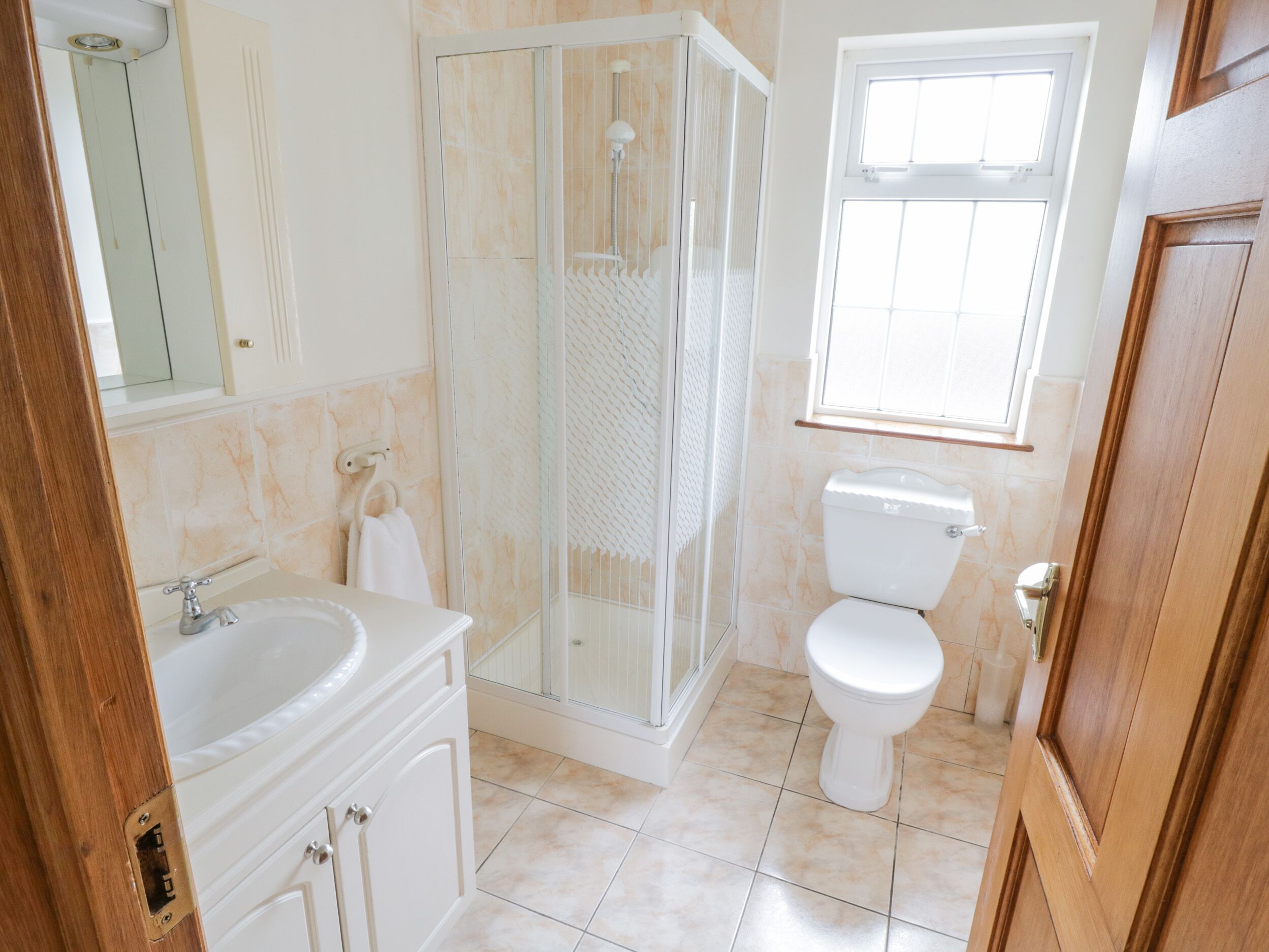 A bathroom with a shower, toilet, sink, and mirror.