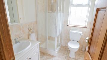 A bathroom with a shower, toilet, sink, and mirror.