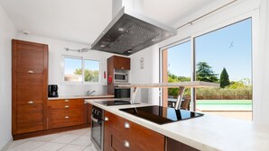 Una cocina moderna con armarios de madera, extractor de acero inoxidable, microondas empotrado y un amplio ventanal con vistas al exterior.