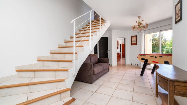 Un interior moderno con una escalera, un sofá, una mesa y una mesa de fútbol.