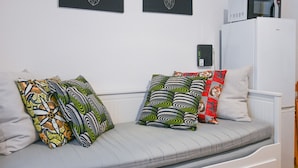 A sofa with patterned cushions, a white wall, and a white refrigerator. - COZY APARTMENT-LAVAPIES- MADRID CITY CENTER (Madrid)