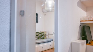 A bedroom with a bed, a bedside table, a lamp, and a shelf with glasses. - COZY APARTMENT-LAVAPIES- MADRID CITY CENTER (Madrid)