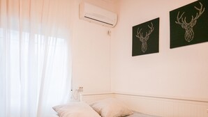 A bedroom with a bed, a window with sheer curtains, an air conditioning unit, and two wall-mounted deer head paintings. - COZY APARTMENT-LAVAPIES- MADRID CITY CENTER (Madrid)