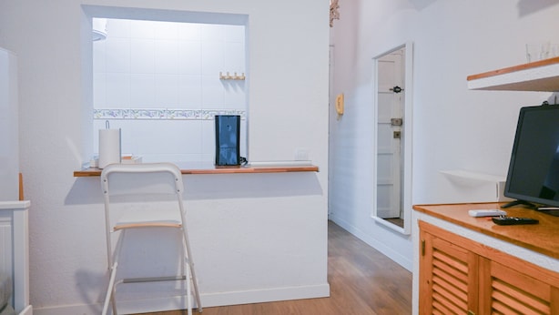 A compact kitchen with white cabinets, a small island, and a wooden counter. - COZY APARTMENT-LAVAPIES- MADRID CITY CENTER (Madrid)