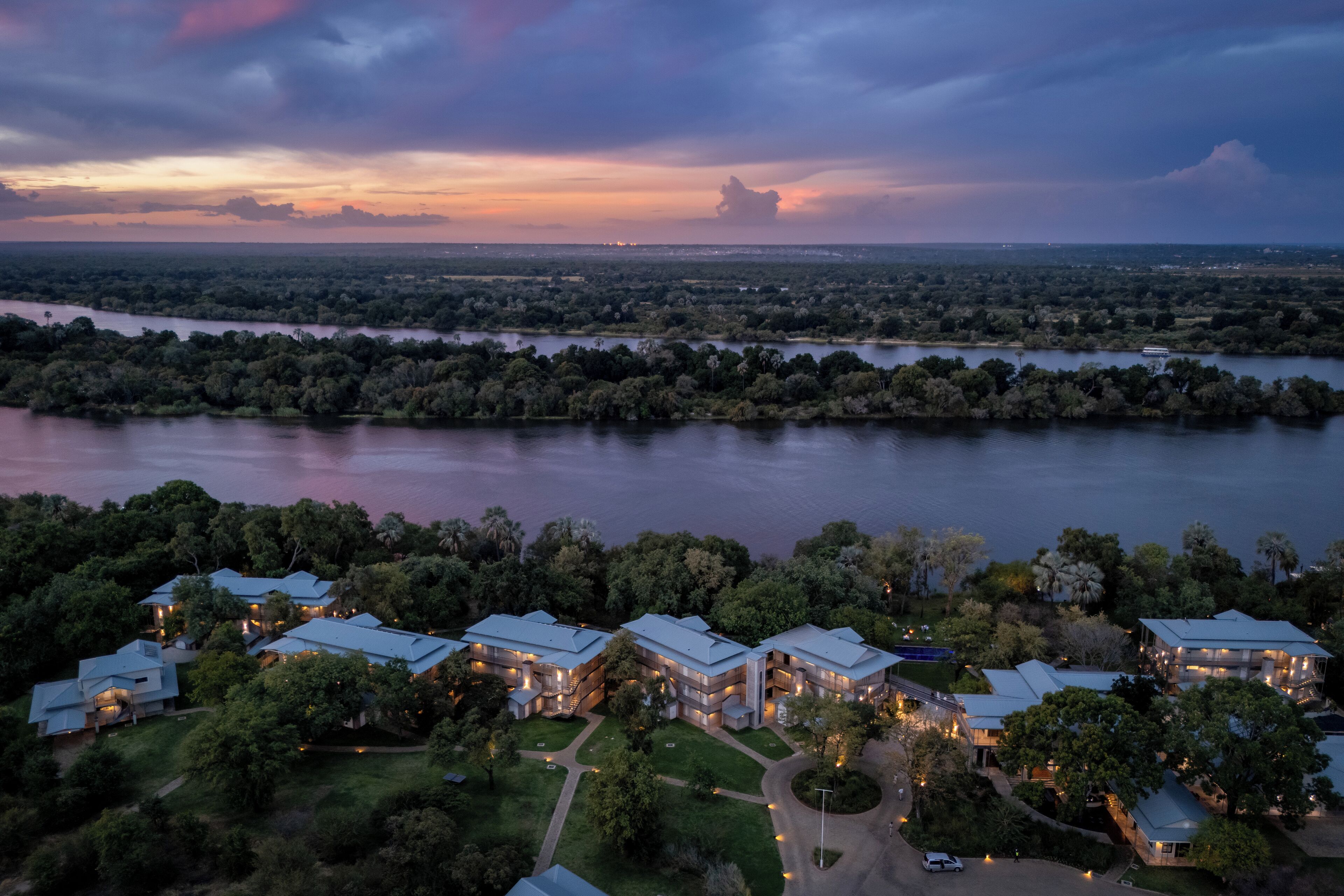 An aerial view of a residential area with multiple houses surrounded by lush greenery and a river.