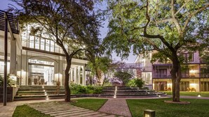 A modern hotel courtyard with a central pathway, surrounded by lush greenery and trees. - Palm River Hotel (Victoria Falls)