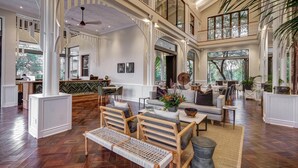 A spacious, high-ceilinged interior with a central seating area, large windows, and a view of the outdoors. - Palm River Hotel (Victoria Falls)