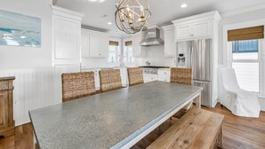 A modern kitchen with white cabinetry, a large island, and a stainless steel refrigerator. - Gulf front home w/6 seater golf cart, priv. pool, direct beach access (Santa Rosa Beach)
