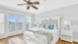 A bedroom with a large bed, two bedside tables, a ceiling fan, and a view through the windows. - Gulf front home w/6 seater golf cart, priv. pool, direct beach access (Santa Rosa Beach)