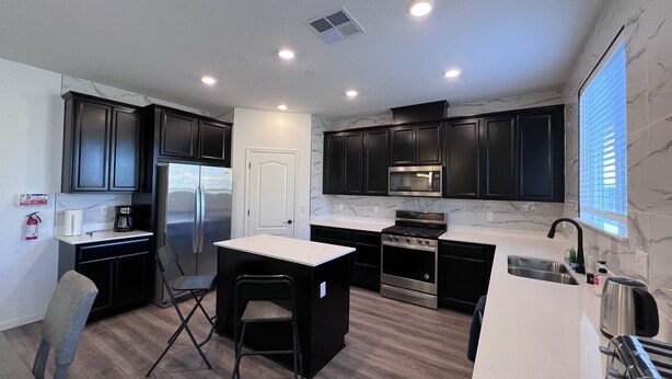 A modern kitchen with dark cabinets, a white countertop, a built-in oven, and a microwave. - Cozy and Comfy Stay at a Bargain! (Woodland)