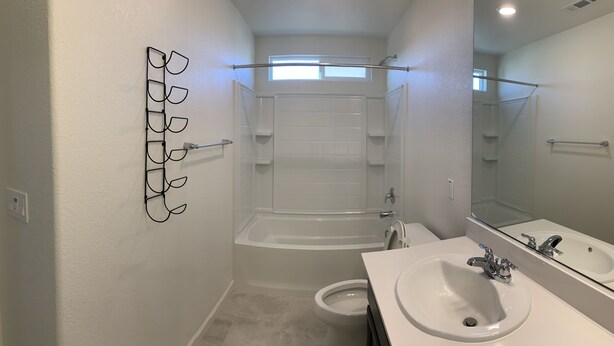Et moderne badeværelse med badekar, bruser, toilet og håndvask.