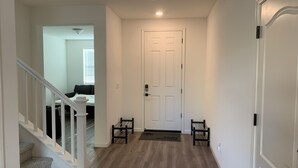 A hallway with a white door, a staircase, and a bench. - Cozy and Comfy Stay at a Bargain! (Woodland)