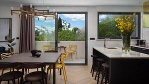 Una cocina moderna con una isla grande, comedor con sillas y vistas a zonas verdes.