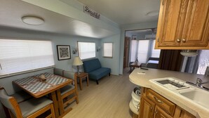 A compact RV interior with a dining table, sofa, and kitchenette. - Tropical Key Largo RV Getaway with Boat Ramp & Golf Cart (Key Largo)