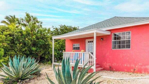 Ein rotes Haus mit einer weißen Veranda und einem kleinen Fenster.