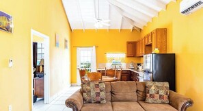 A living room with a sofa, coffee table, and a view of the kitchen.