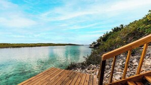Une terrasse en bois qui mène à une étendue d’eau calme, sous un ciel dégagé.