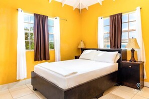 A bedroom with a bed, nightstands, and curtains.