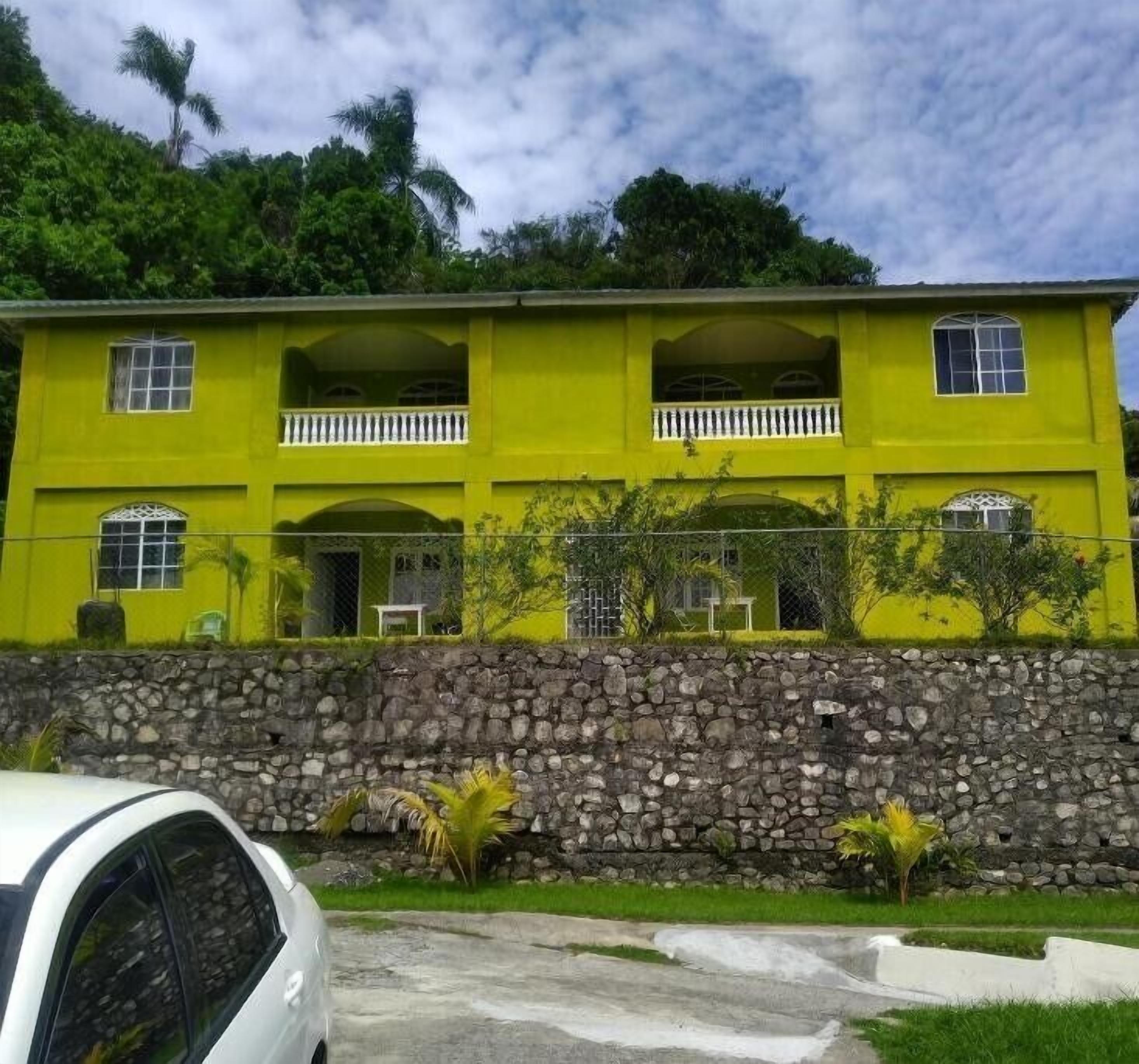 A two-story building with a stone wall foundation, multiple windows, and a balcony.