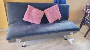 A dark blue sofa with two pink cushions and a circular accent on the armrest. - Chalk Sound Lagoon Cottage with Kayak Dock (Providenciales)