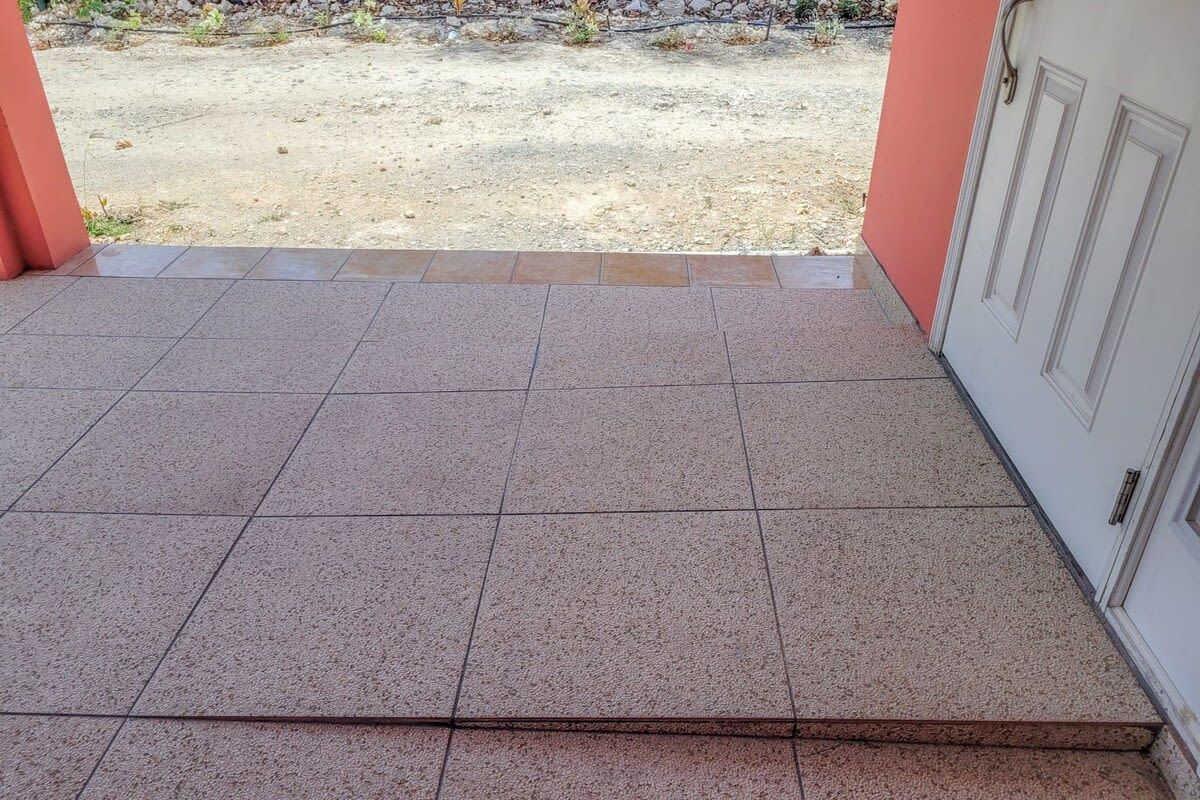 Un patio carrelé avec vue sur une cour en gravier.
